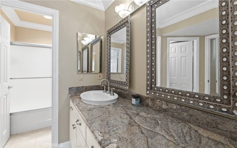 Granite countertops with custom mirrors and light fixture.