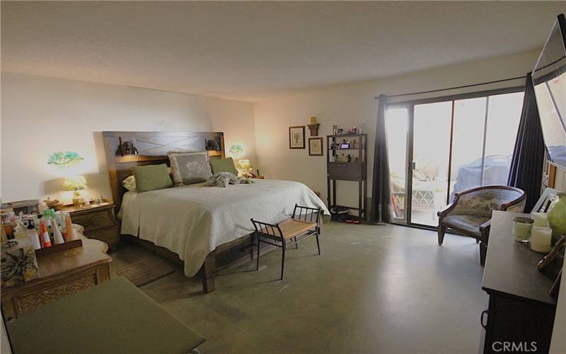 Large oversized primary bedroom with concrete floors.