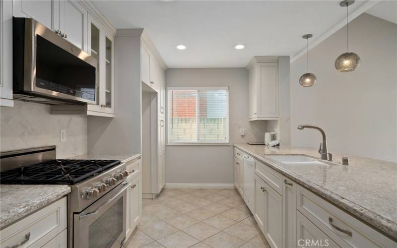 The upgraded kitchen includes newer solid wood cabinetry, beautiful granite countertops, breakfast bar, recessed lighting, a custom stone herringbone finished backsplash, and stainless steel appliances.