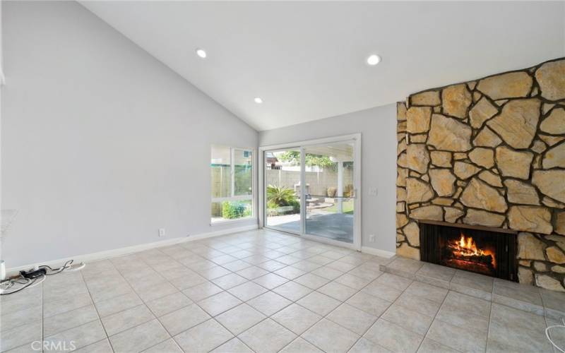 The large separate family room features high ceilings, recessed lighting, a fireplace, and garden views.