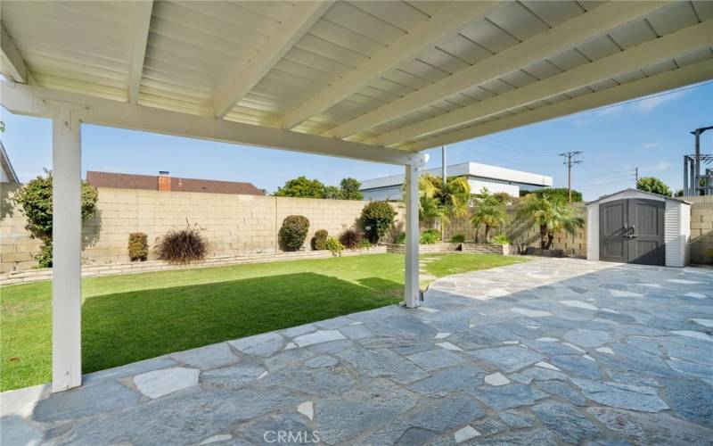 The private backyard offers a large covered patio, custom stone finished patio, beautiful fountain, and a storage shed.