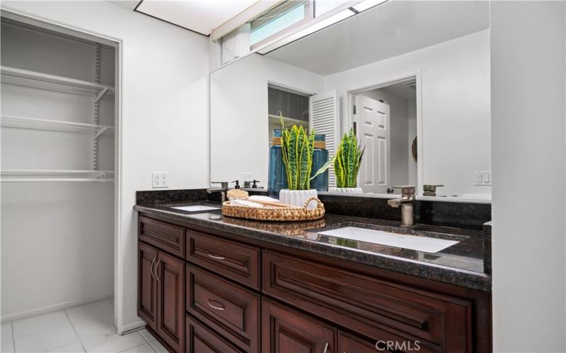 Primary Bathroom vanity with quartz countertop, dual sinks, and linen closet