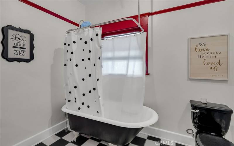 Downstairs bathroom with claw foot tub and black porcelain sink and toilet.