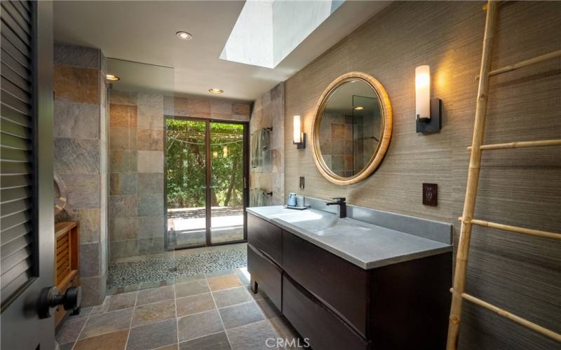The handsome main bathroom offers slate tiled floors that are carried up the walls and a large skylight that illuminates the room.