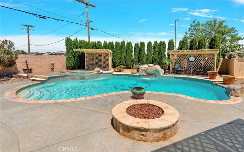 Fire pit adjacent to pool. Several cabanas surround the pool.