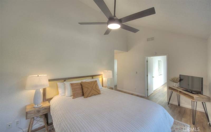 Another view of the large primary bedroom with vaulted ceilings and a brand new ceiling fan.