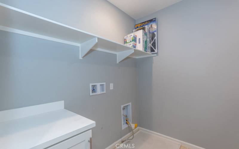 spacious laundry area with built-in cabinet and countertop, and shelving
