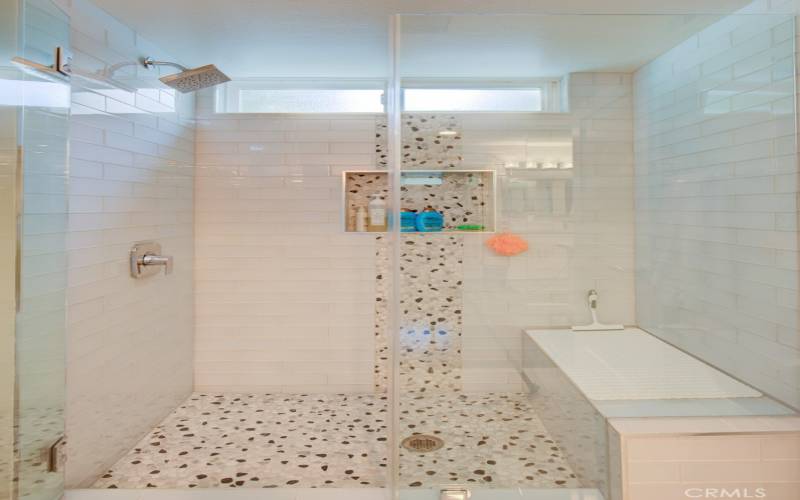 Right-side bathroom has a shower with seat and convenient accessory shelf.