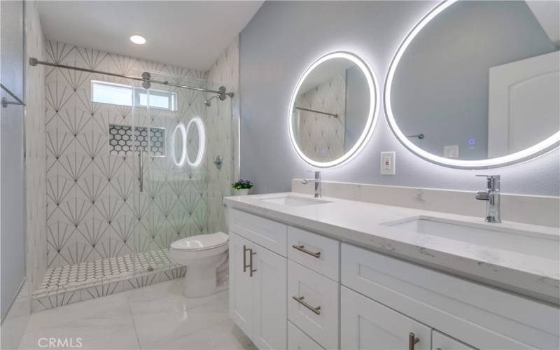 The front bath with gorgeous tile work in the walk-in shower, dual sinks, and lighted mirrors