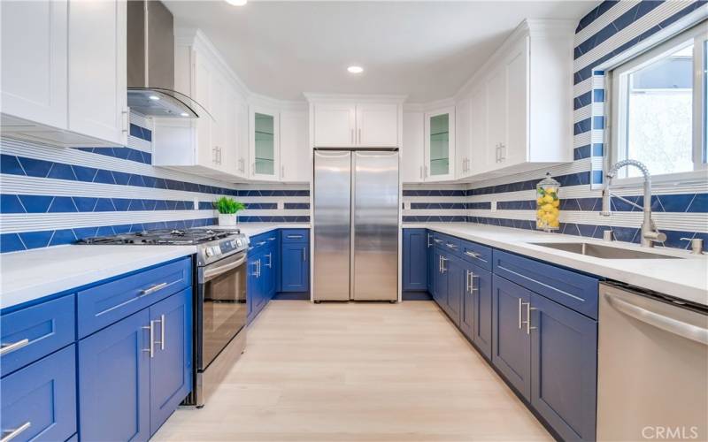 Wow! This kitchen is stunning with quartz countertops, custom tile backsplash, two-tone soft-close Shaker cabinetry, recessed lighting, and stainless steel appliances