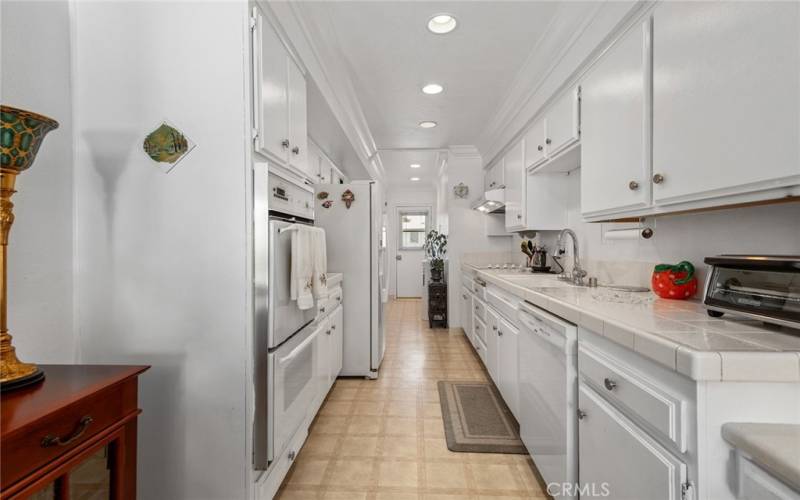 Large Galley kitchen with pantry and door to balcony in back.