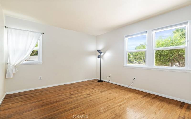 The primary bedroom boasts hardwood floors and windows that look out the front and side of the home.