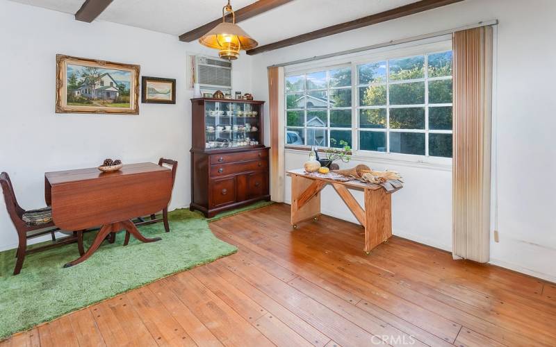 The dining room fittingly adjoins the kitchen and with its wood beamed ceilings, sparkling picture window and original hardwood floors, it is perfect for any occasion.