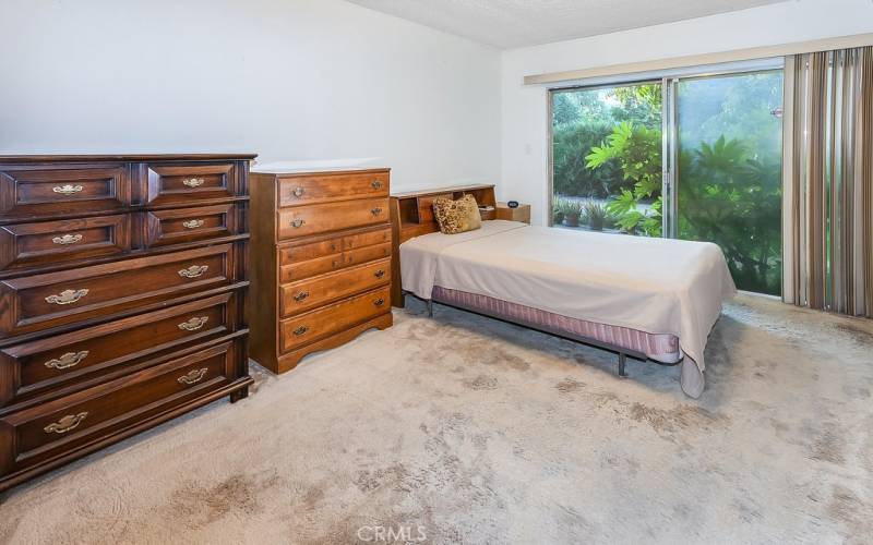 The primary bedroom is drenched in natural light and is enriched by overhead lighting, dual closets with overhead storage, and sliding glass doors that lead to the backyard,