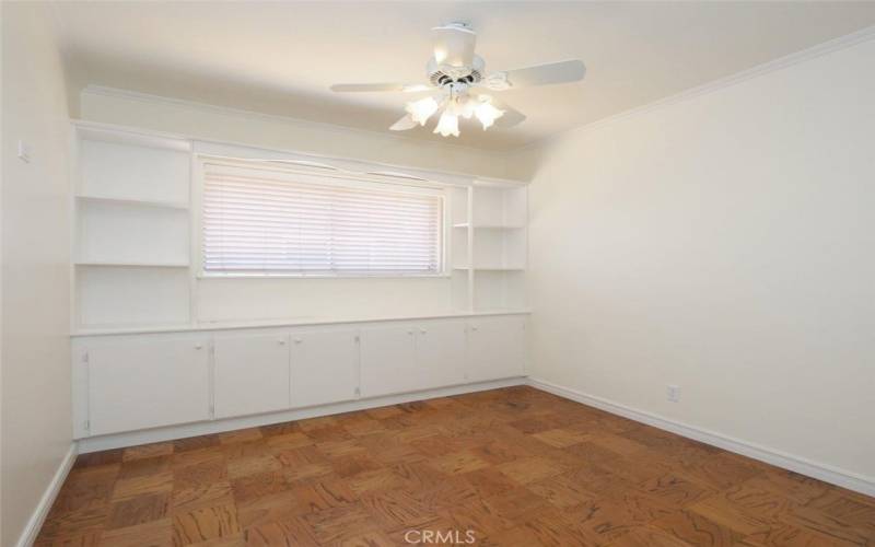 Bedroom 2 with extensive built-ins, refinished wood floor and ceiling fan.