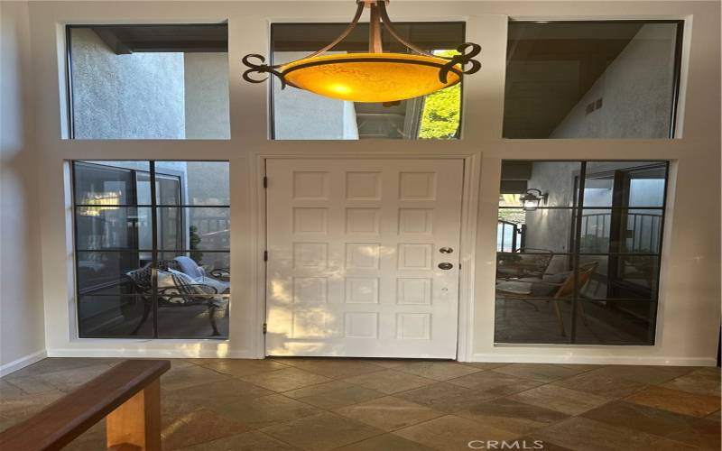 Newly painted Entry door that is now white and has fantastic custom light over head and lovely flag stone flooring with lots of windows.