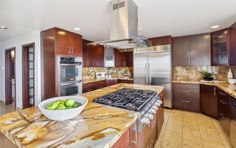 The custom kitchen has a 6 gas burner stove top with range hood, double ovens, double door Kitchen Aid refrigerator.  Custom granite counter tops.  Down the hallway has a walk-in pantry and large bathroom and door to the garage