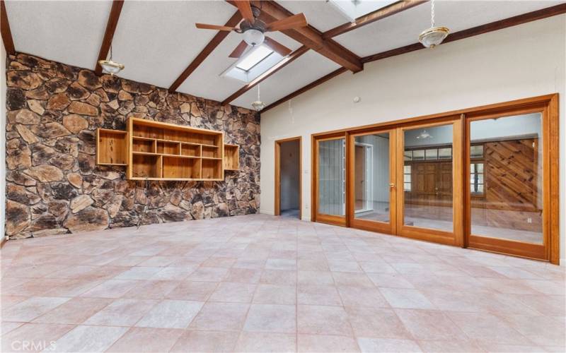 The living room features built-in shelving, skylights, and high open-beam ceilings.