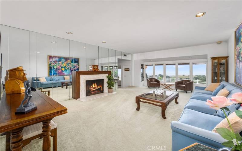 Formal living room view from foyer/front door area with fireplace and view