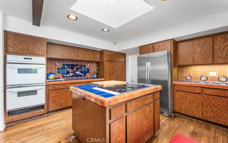 Kitchen with double convection oven, electric stove top, custom spanish glazed tile with koi fish & skylight.