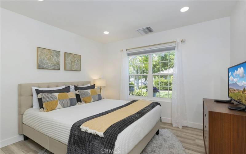 spacious Secondary bedroom with bright window and wood like flooring, recessed lighting.