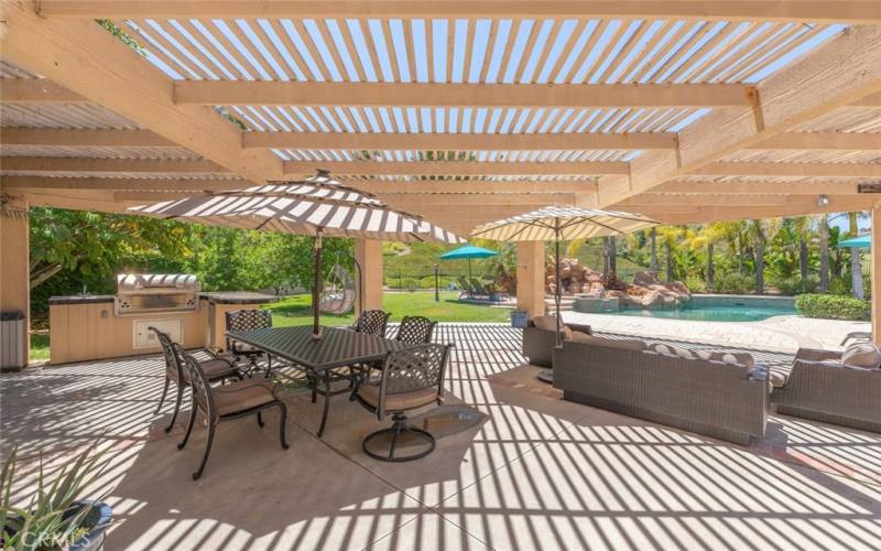  Expansive outdoor entertaining area with ample seating under a pergola.
