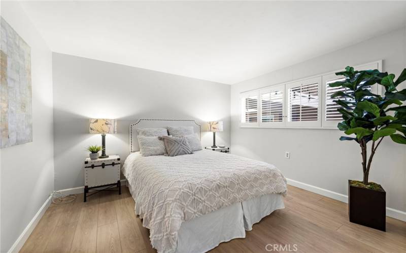 The secondary bedroom has luxury laminate plank flooring, plantation shutters, and designer paint.