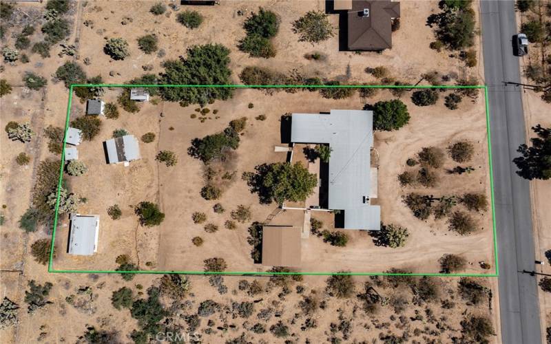 Aerial of property - main house + guest house are the large structure attached to one another via garage and each with their own entrance.  Adjacent, you will find the carport (brown roof closest to the main house).  At the rear of the property is another possible unit on the far left (bathroom in place), chicken coop, and animal structures.