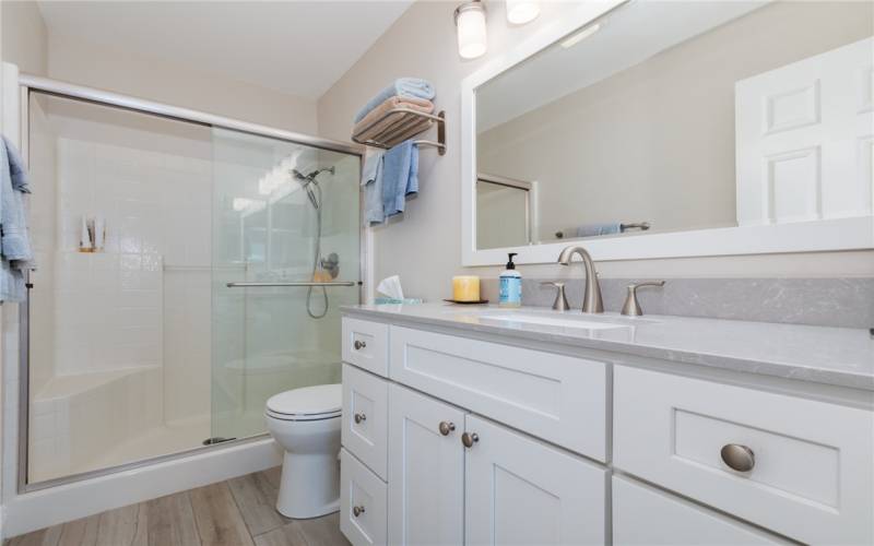 Downstairs full bathroom remodeled porcelain flooring , walk -in sliding glass door shower , marble countertop