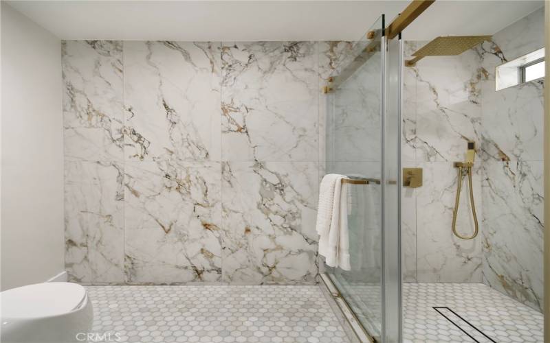 Marble tiled floors and porcelain tile walls in primary bathroom