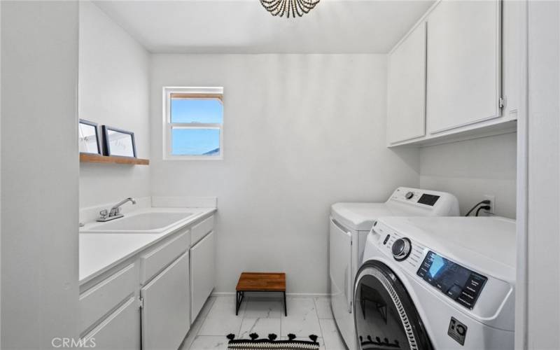 A workable laundry room with a large sink and upstairs