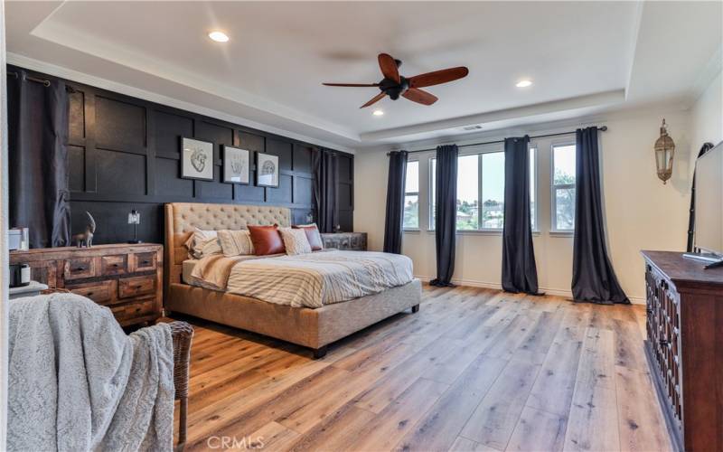 Primary suite with new luxury vinyl flooring land custom wall behind bed.