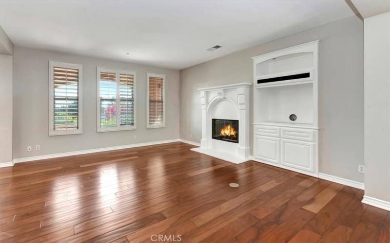 Living room with gas fireplace, built-in's and wood floors & plantation shutters.