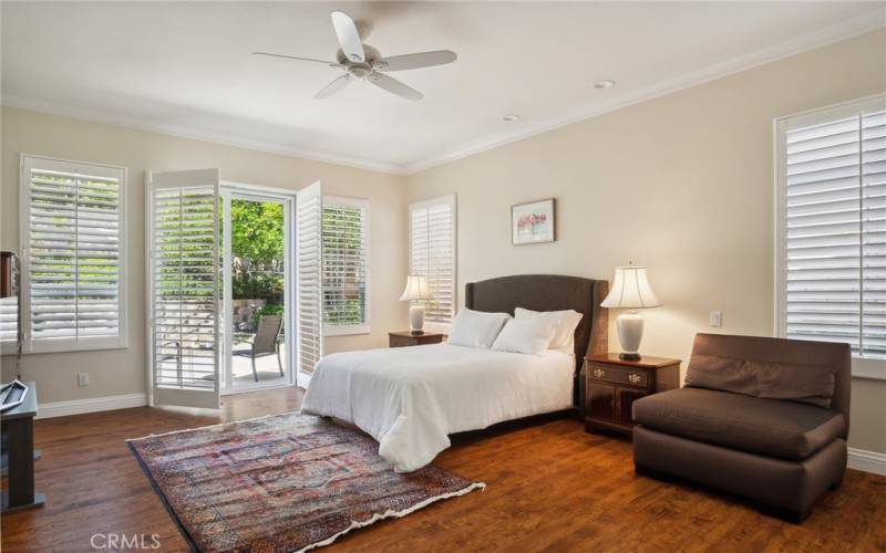 The primary bedroom has big windows and a sliding door that opens to the patio.