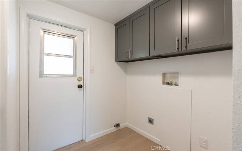 Separate laundry room with new cabinetry, back door allows for easy access to the carport