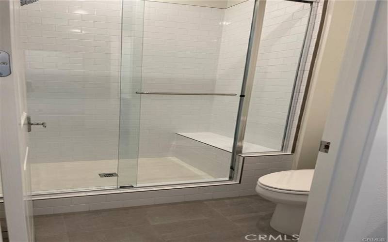 Large bathroom with walk-in shower and dual sinks.