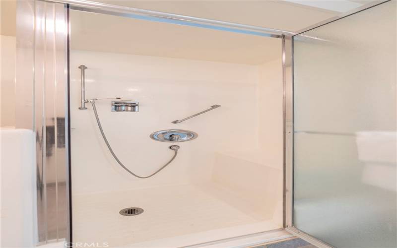 Cut-down, walk-in shower with grab bars.