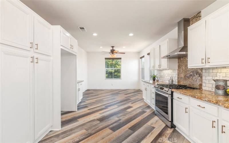 The center of the kitchen hosts a cozy dining nook, surrounded by windows that flood the space with natural light This kitchen is perfectly designed for both cooking and casual dining, making it a central gathering spot in the home