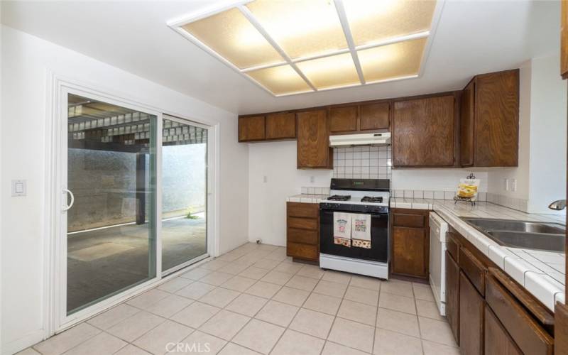 Kitchen with tile counters, tile flooring, sliding glass doors that open to covered patio