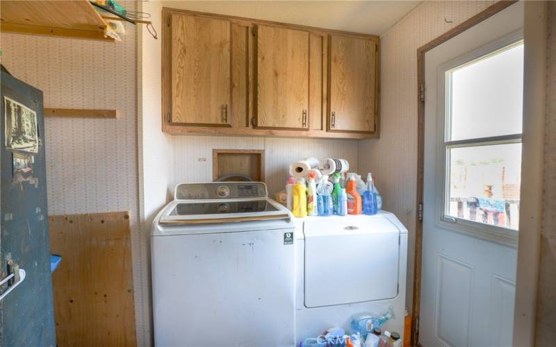 The laundry room offers cabinets for storage and a door to the outside.