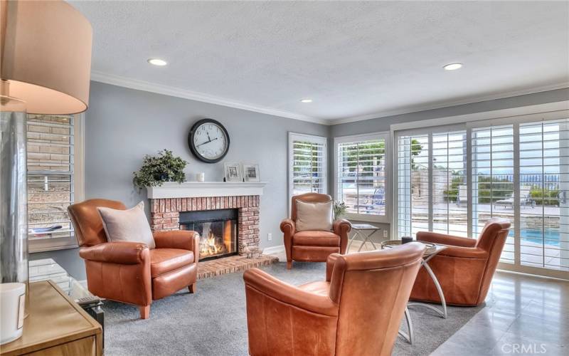 Enjoy gatherings in the generously-sized living area graced by a fireplace, huge windows and glass sliding doors that lead out to the backyard with pool and spa