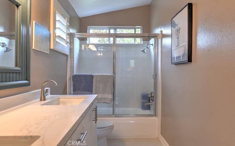 Upstairs bathroom with tiled shower in tub and dual vanity sinks