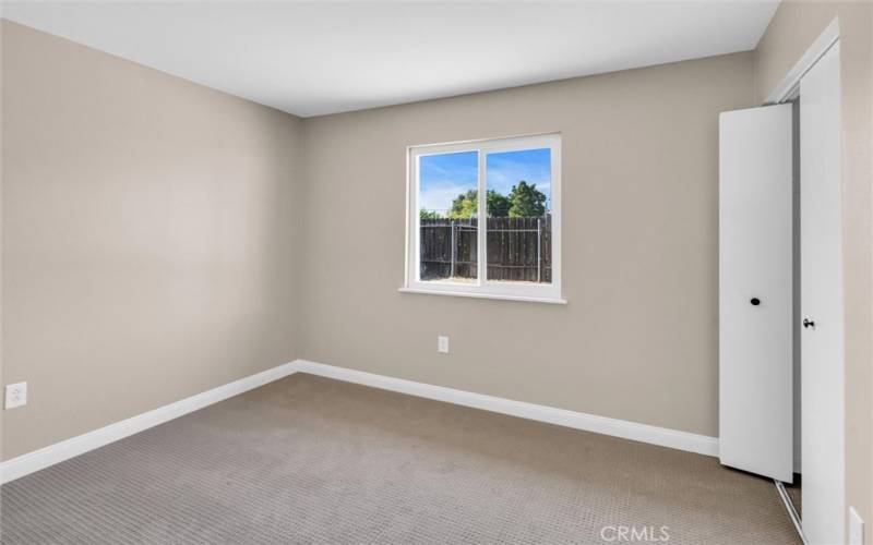 Bedroom 2 with low pile carpet and backyard view