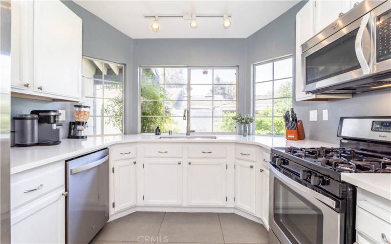 Kitchen with farmer sink, dishwasher, gas range, built in microwave, lots of cabinet storage and quartz counter tops.