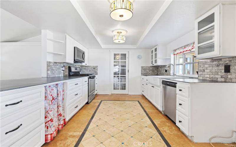 This galley style kitchen is open to living room, tiled floor and crisp white cabinetry with glass doors. The bay window is great for the chef who wants herb to grow here!