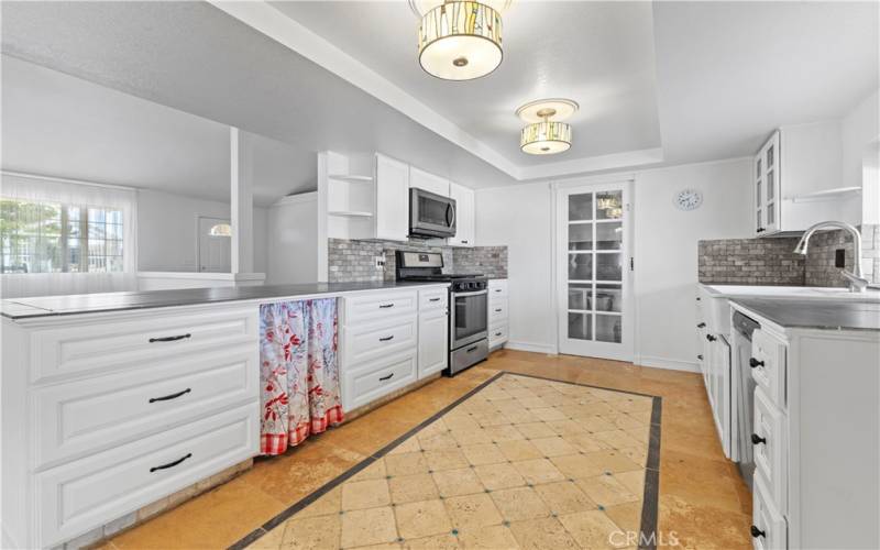 Stainless steel appliances included are the Whirlpool 5 burner gas range, the LG microwave range hood, stainless steel Fridgidaire dishwasher and white porcelain farm style sink.