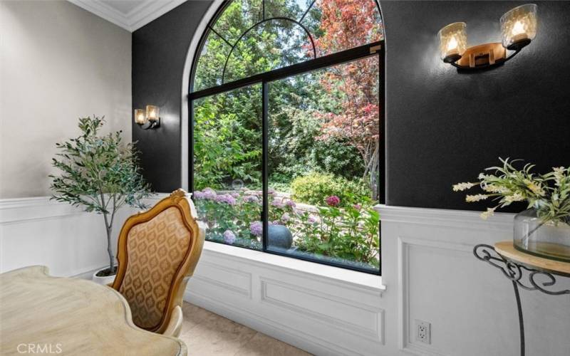 The dining room showcases an 11-foot ceiling with gorgeous views of the outside garden area, perfect for  entertaining guests. Custom lighting and paneled walls enhance the dining experience.