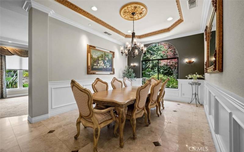 The dining room showcases an 11-foot ceiling with gorgeous views of the outside garden area, perfect for  entertaining guests. Custom lighting and paneled walls enhance the dining experience.