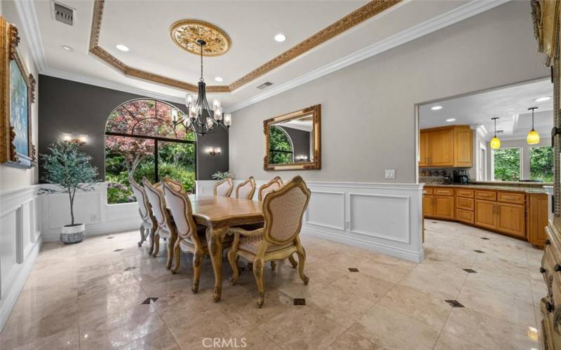 The dining room showcases an 11-foot ceiling with gorgeous views of the outside garden area, perfect for  entertaining guests. Custom lighting and paneled walls enhance the dining experience.