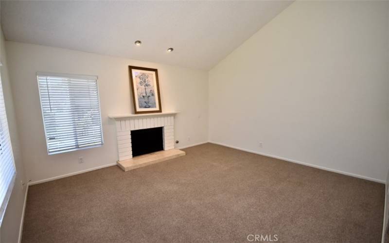 The living room is cozy and inviting with plush carpeting, perfect for relaxation and family gatherings.